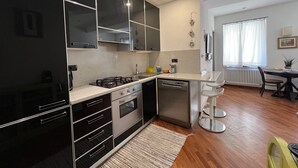 A modern kitchen with black cabinets, stainless steel appliances, and a wooden dining area.