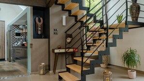 Una escalera moderna con escalones de madera y barandillas de metal negro, que conduce a un segundo piso.