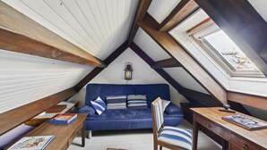 Ein gemütliches Dachzimmer mit einem blauen Sofa, einem Holztisch und einem Oberlicht.
