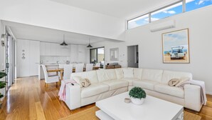 A modern living room with a large white sectional sofa, a white coffee table, and a potted plant.