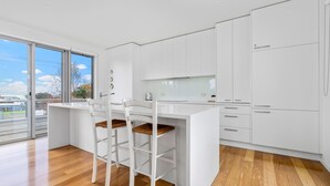 A modern kitchen with white cabinetry, a wooden countertop, and a dining area with white chairs.