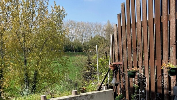 Un espace patio avec une table blanche, des plantes en pot et une clôture en bois.