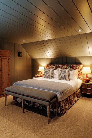 Un dormitorio con una cama grande, cabecera de madera y dos mesitas de noche con lámparas.