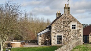 A stone building with a small window and a door, surrounded by a stone wall and a grassy area. - JOIVY Lathallan Mill Farmhouse (Leven)