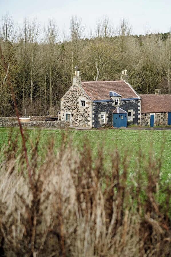 A stone house with a red-tiled roof, a blue door, and a small attached shed. - JOIVY Lathallan Mill Farmhouse (Leven)