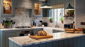 A modern kitchen with a marble island, dark cabinetry, and pendant lighting. - JOIVY Lathallan Mill Farmhouse (Leven)