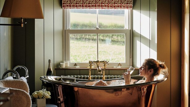 A bathroom with a vintage bathtub, a window with a patterned valance, and a chair. - JOIVY Lathallan Mill Farmhouse (Leven)