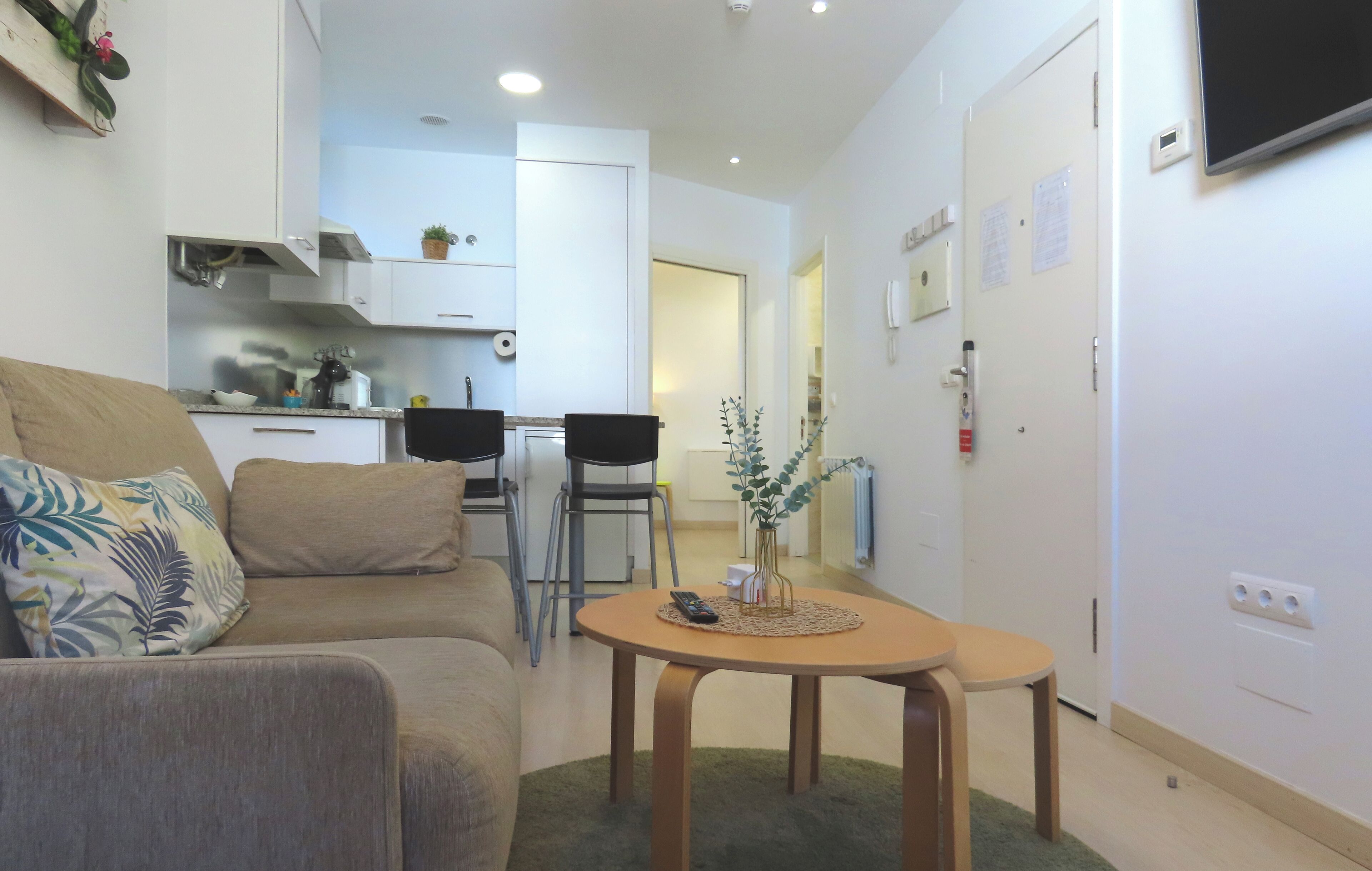 Un espace de vie compact comprenant un canapé, une petite table à manger et un coin cuisine à l’arrière-plan.