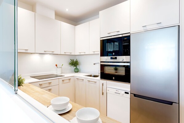 Una cocina moderna con armarios blancos, electrodomésticos de acero inoxidable y encimera de madera.