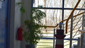 Uma escada com corrimão, um extintor de incêndio, uma planta em vaso e um modelo de farol.