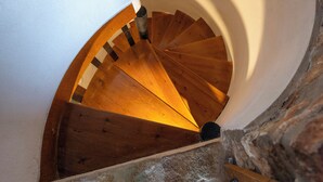 A spiral staircase with wooden steps and a stone wall. - Elena's Traditional DreamHouse (Paros)