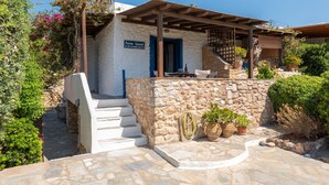 A stone house with a wooden porch, a staircase, and potted plants. - Elena's Traditional DreamHouse (Paros)