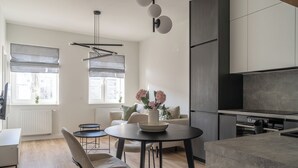 Eine moderne Küche mit Essbereich, ausgestattet mit einem runden Tisch, Stühlen und einer Vase mit Blumen.
