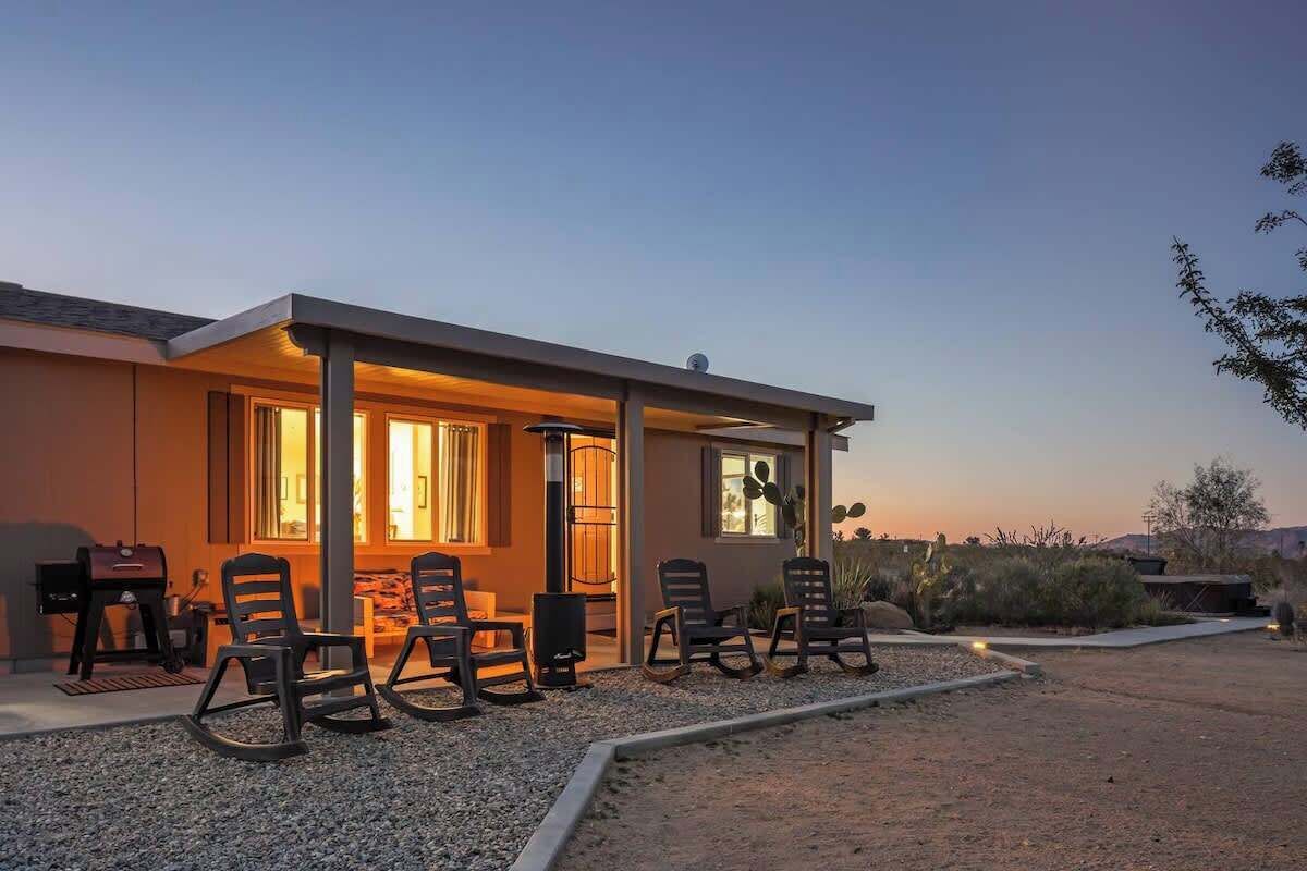 A modern house with a patio area featuring outdoor seating and a barbecue grill.