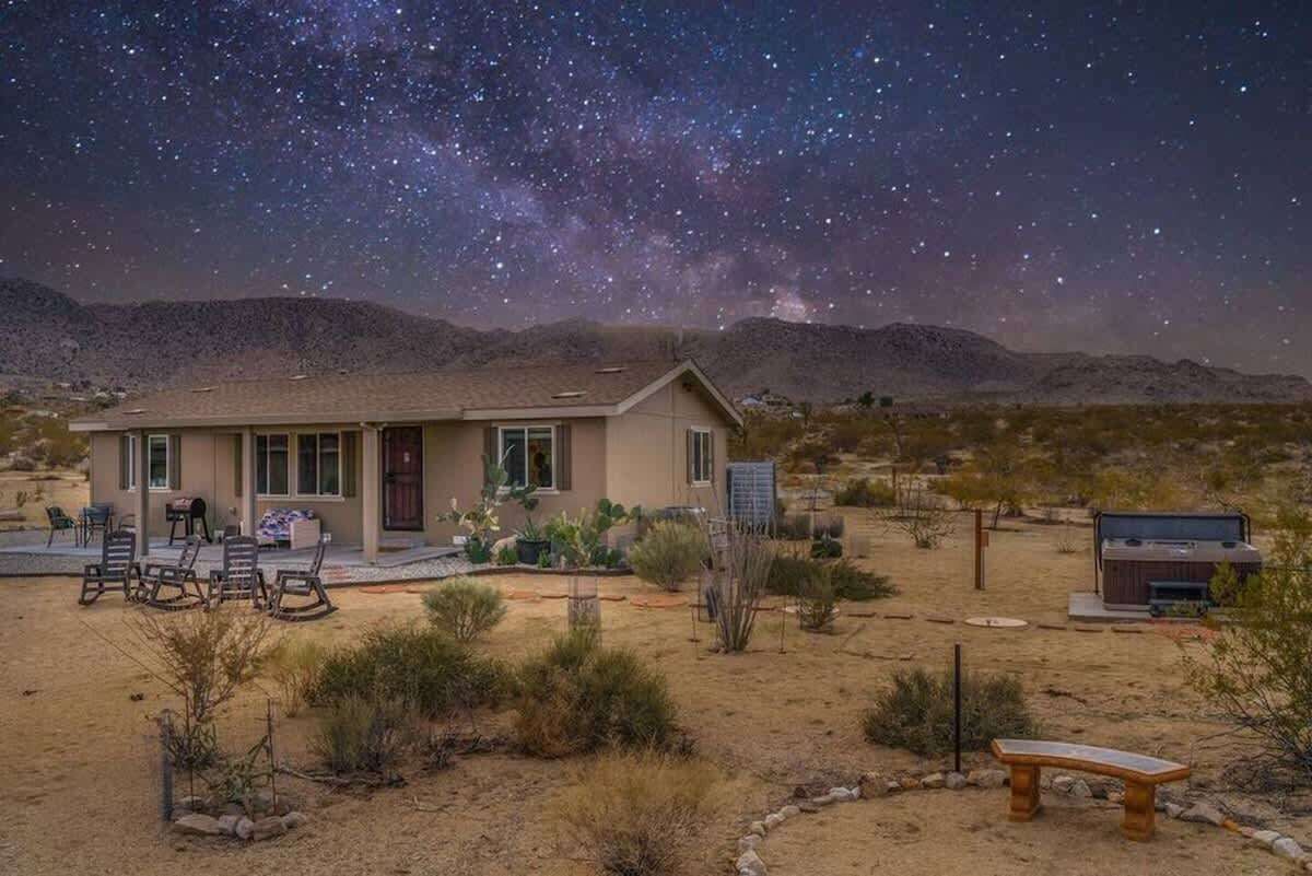 A desert house with a patio, a hot tub, and a starry night sky.