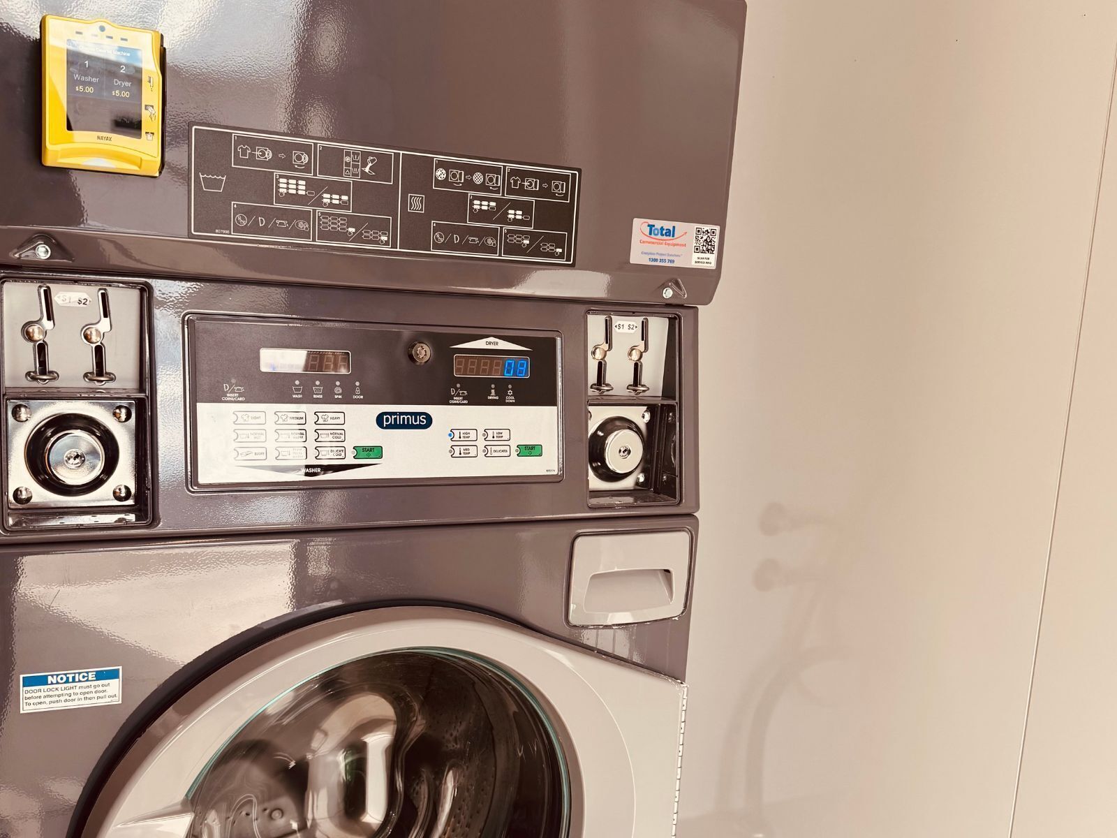 A commercial washing machine with a control panel, a digital display, and a door lock mechanism.