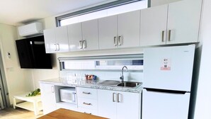 A modern kitchen with white cabinets, a built-in oven, and a refrigerator. - Resort on Cedar (Windang)