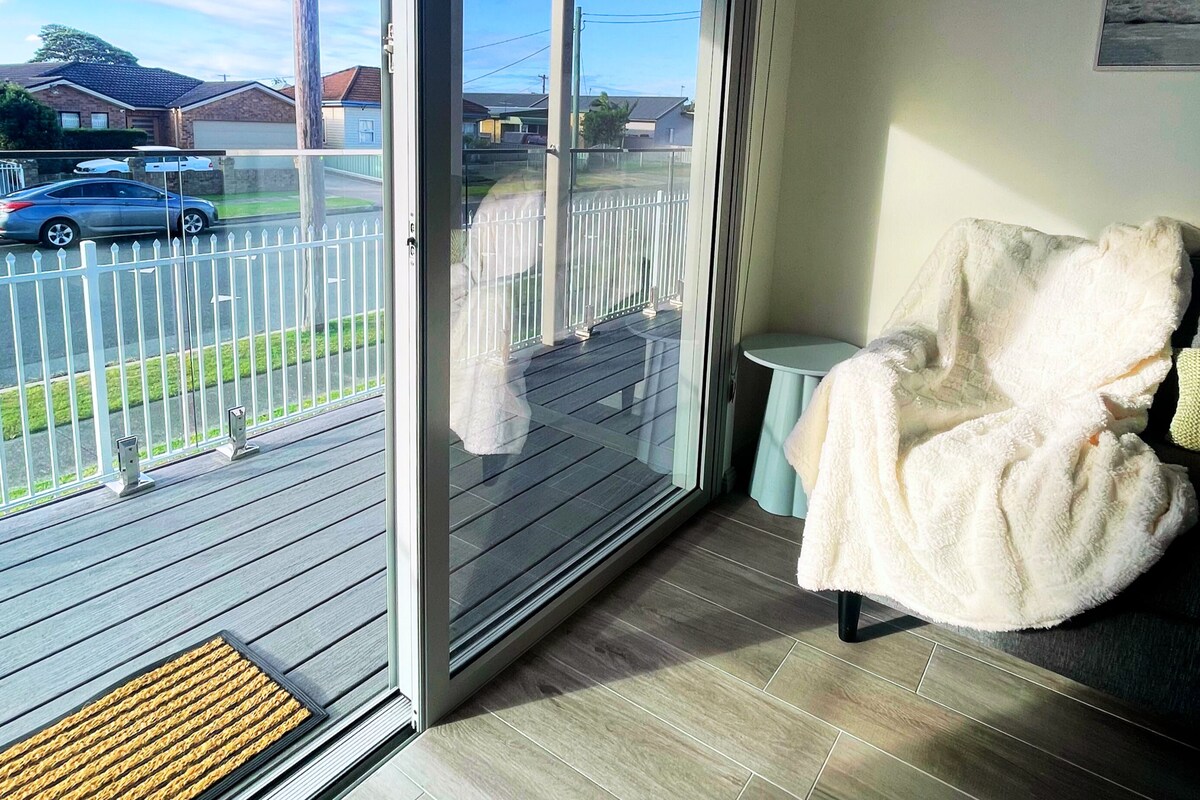 A room with a sliding glass door leading to a balcony, a chair, and a small table.