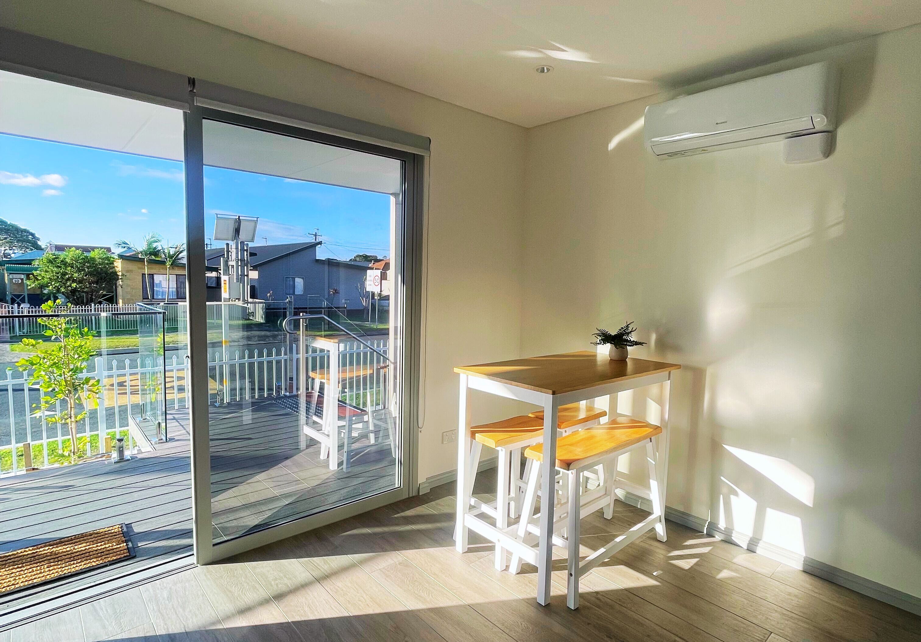 A balcony with a sliding door, a wooden table with two chairs, and a potted plant.