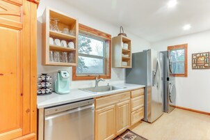Una cocina moderna con armarios de madera, lavavajillas, refrigerador y cafetera.