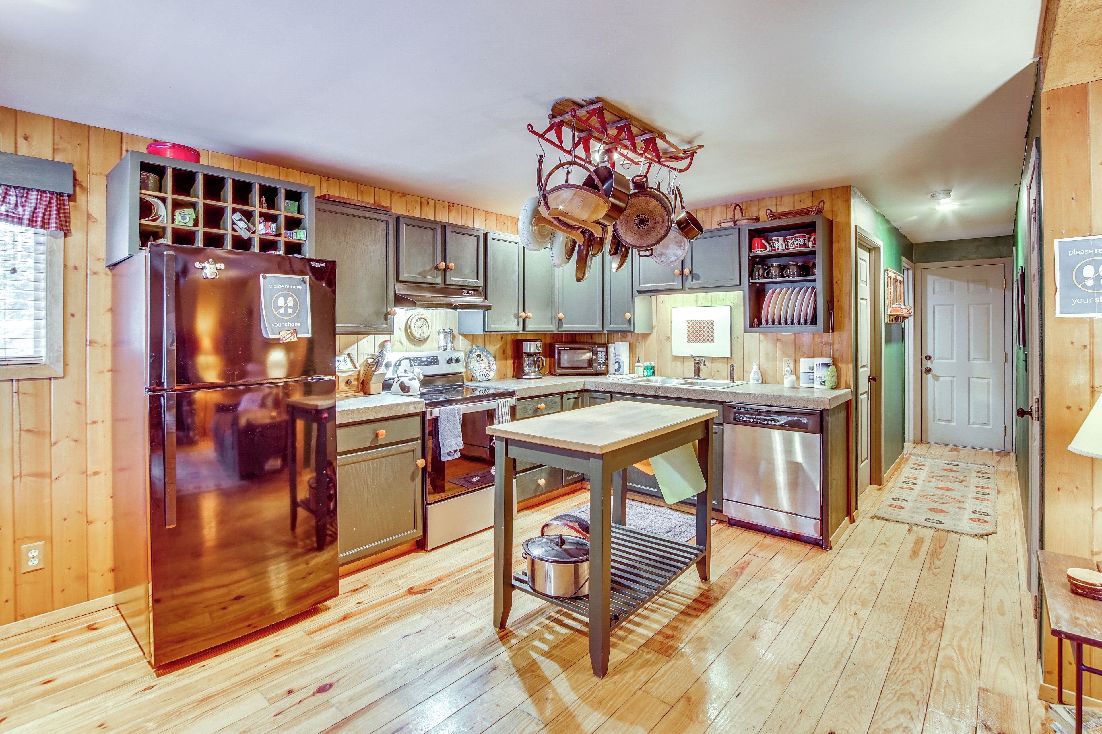 A kitchen with wooden cabinets, a stainless steel refrigerator, a microwave, and a sink.