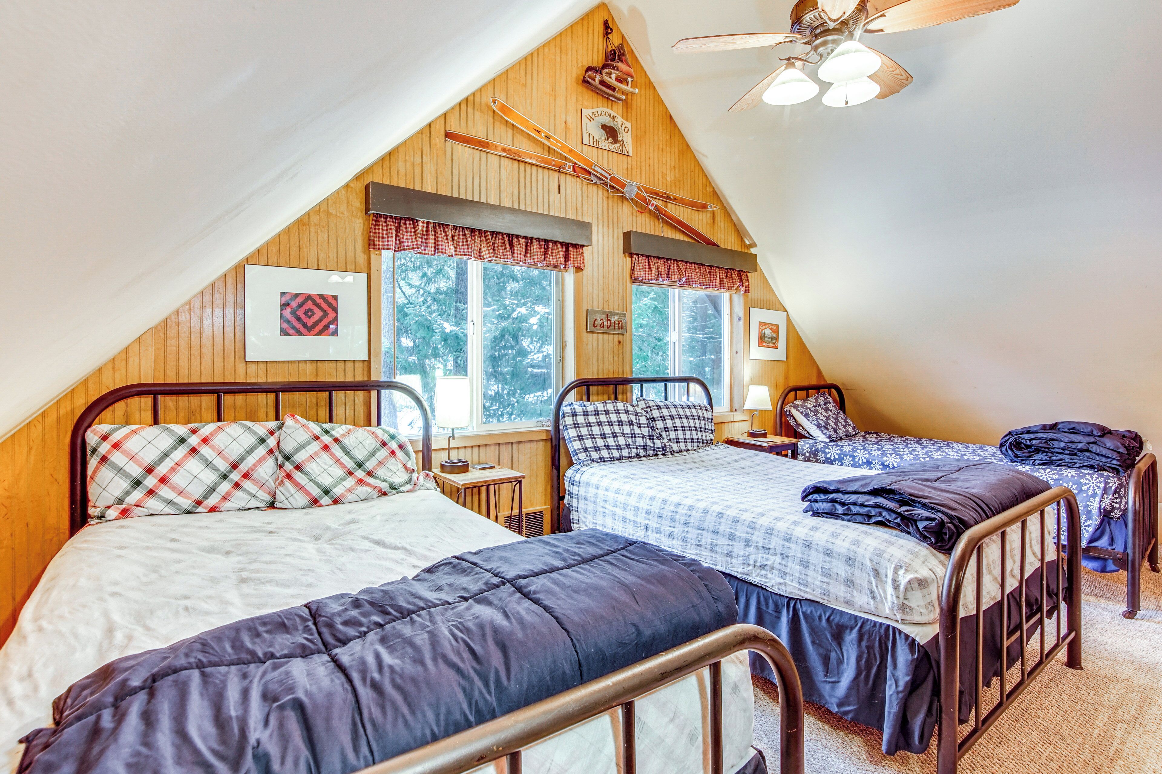 A cozy attic bedroom with two beds, wooden walls, and a sloped ceiling.