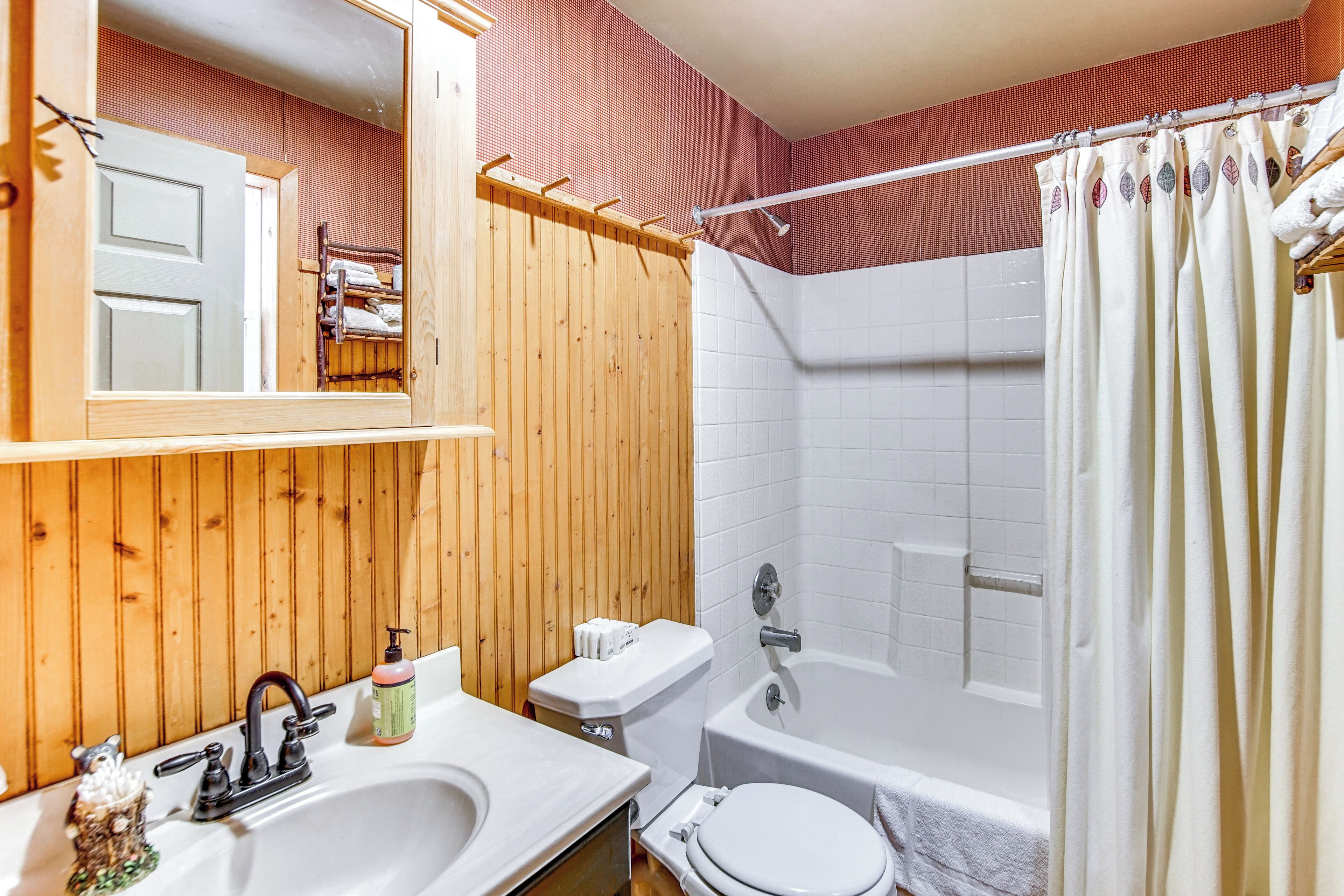 Une salle de bain avec un meuble-lavabo en bois, un lavabo, des toilettes et une baignoire.