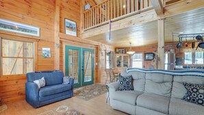 A spacious living room with two sofas, a dining area, and a kitchen with hanging pots. - 2 Mi to Skiing: Casper Cabin w/ Mtn Views! (Casper)