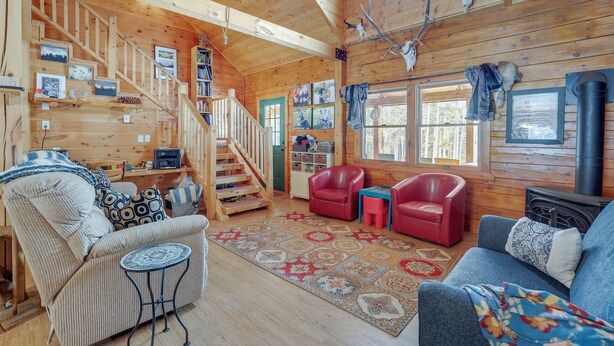 A cozy cabin interior with a wooden staircase, a fireplace, and a living area with a sofa and chairs. - 2 Mi to Skiing: Casper Cabin w/ Mtn Views! (Casper)