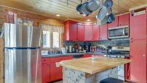 A kitchen with red cabinets, a stainless steel refrigerator, a microwave, and a stove. - 2 Mi to Skiing: Casper Cabin w/ Mtn Views! (Casper)