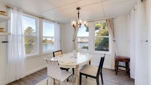 A dining room with a round table, chairs, and a chandelier. - Walk to Beach: Riverside Retreat in Seaside! (Seaside)