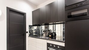 A modern kitchen with dark cabinetry, a black countertop, and a built-in oven.