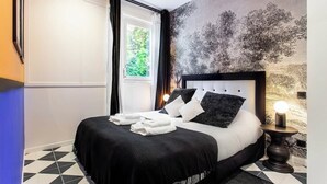 A modern bedroom with a bed, a nightstand, a wall-mounted lamp, and a window with curtains.