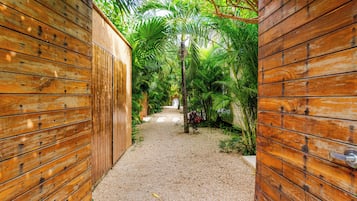 Ein hölzerner Weg führt durch einen üppigen Garten, der von Holzzäunen gesäumt ist.