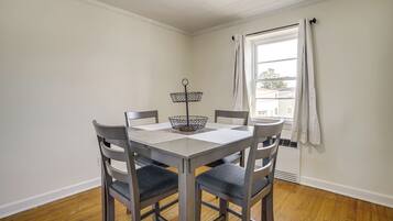 A dining area with a table, chairs, and a window with curtains.
