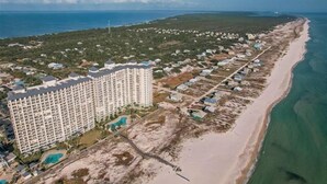Et højt hotel med mange etager, beliggende ved stranden, og et lille poolområde.