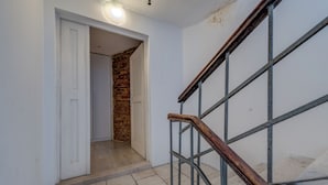 A hallway with a wooden handrail, a white door, and a brick wall. - The Code Luxury Rooms (Split)