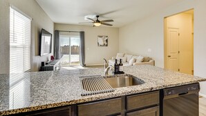 A kitchen with granite countertops, a stainless steel sink, and a ceiling fan. - Hike, Sightsee & Explore: Home in Colorado Springs (Colorado Springs)