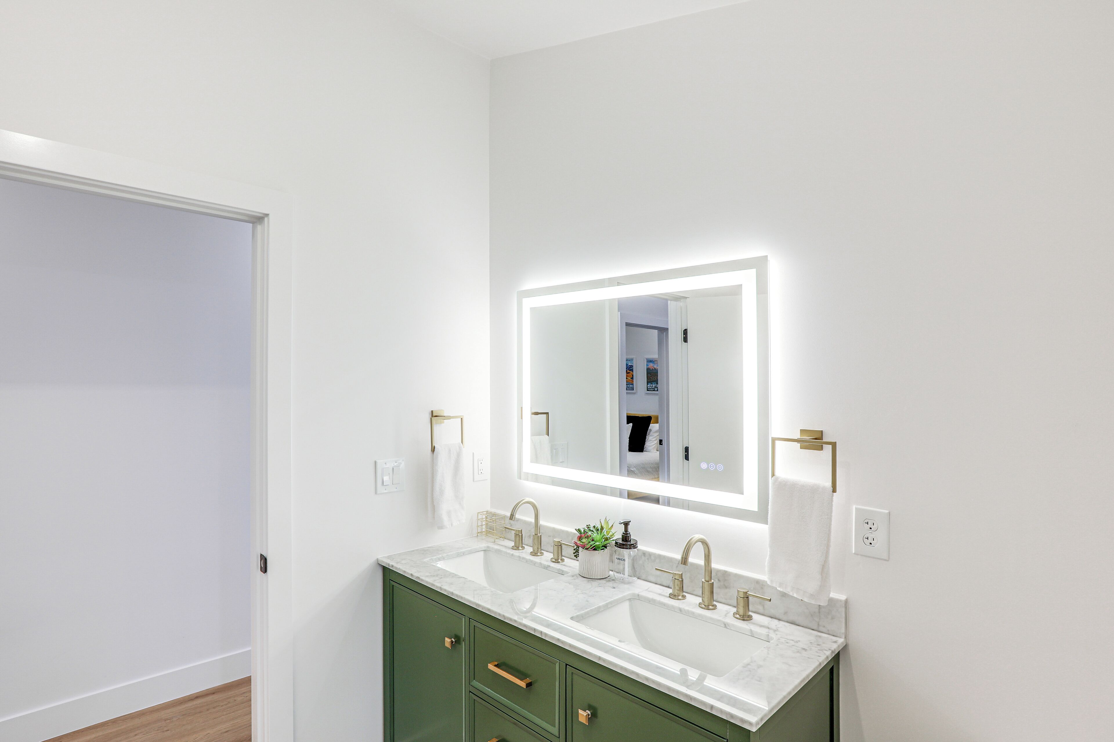 Une salle de bain moderne avec deux lavabos, un grand miroir et des meubles de couleur verte.