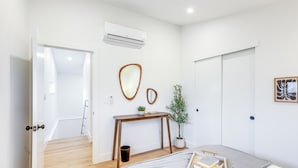 A modern bedroom with a bed, bedside table, and a potted plant. - < 1 Block to City Park: New-build Apt in Denver! (Denver)