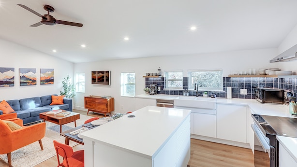 A modern living room with a sofa, coffee table, and a dining area. There is a kitchen with a stove, microwave, and sink. - < 1 Block to City Park: New-build Apt in Denver! (Denver)