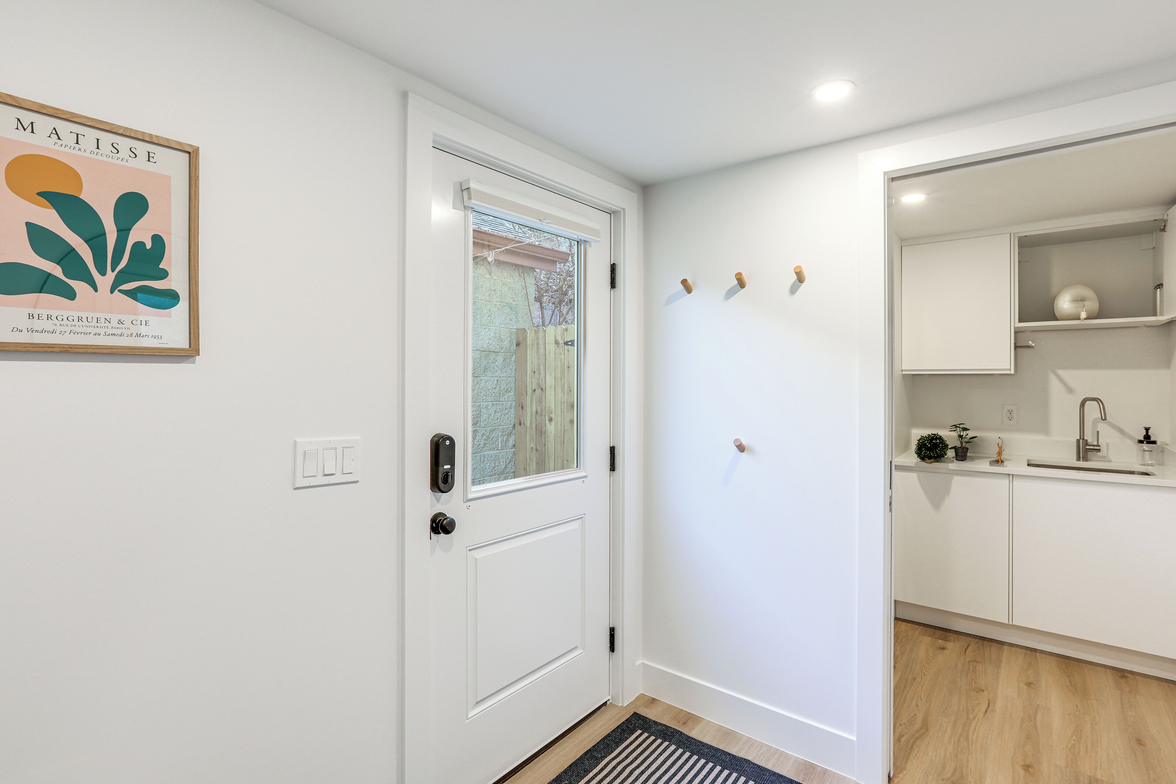 A modern kitchen with white cabinets, a built-in oven, and a sink.