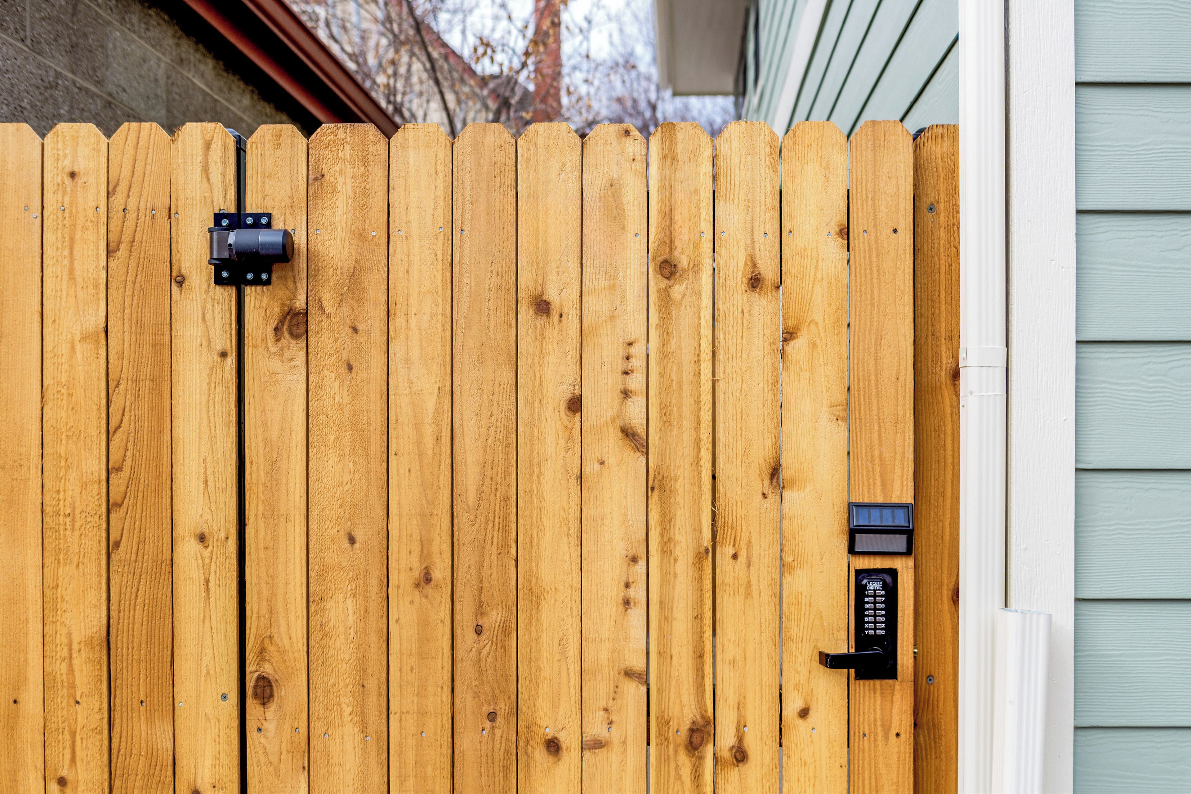 A wooden fence with a gate and a keypad lock.