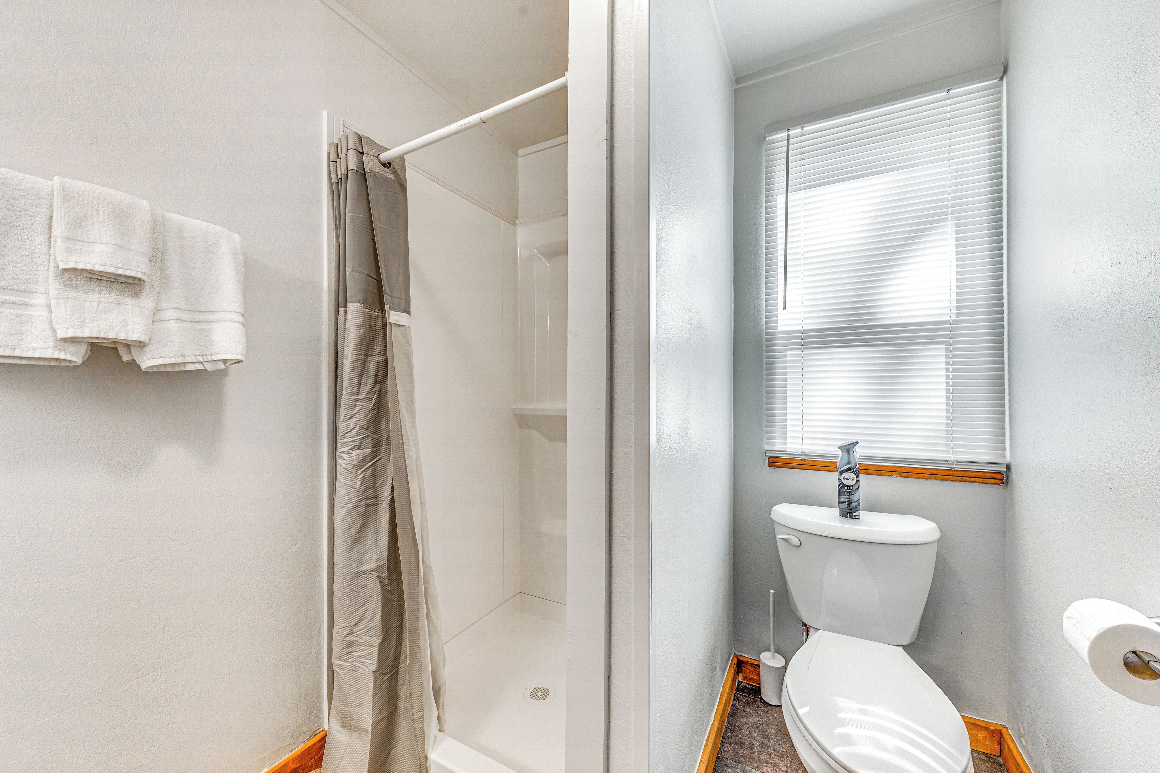 A bathroom with a shower, toilet, and a towel rack with two towels.