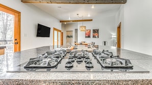 A spacious room with a long table, a fireplace, and a television on the wall.