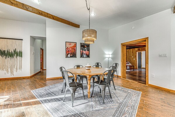 A dining area with a round table, chairs, a hanging light fixture, and artwork on the walls. - Walk to Midtown Ruidoso: Modern-rustic Cabin (Ruidoso)