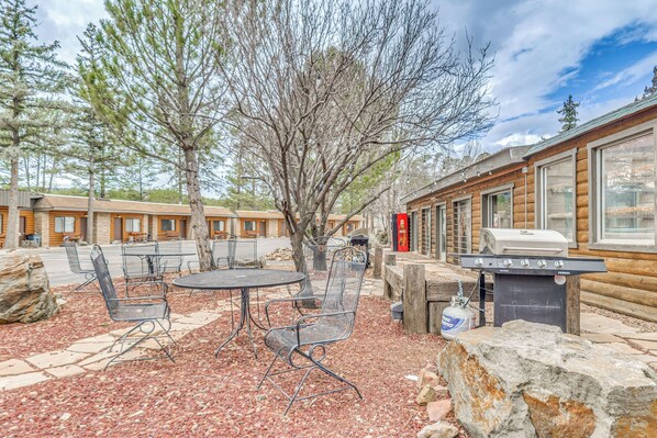 A log cabin with outdoor seating, a grill, and a stone fireplace. - Walk to Midtown Ruidoso: Modern-rustic Cabin (Ruidoso)