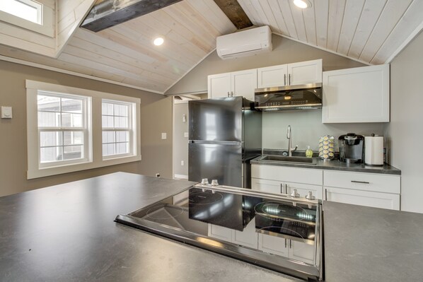 A modern kitchen with a stainless steel refrigerator, built-in oven, and white cabinetry.
