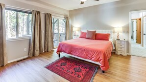Un dormitorio con cama, ventilador de techo, mesita de noche, lámpara y ventana con cortinas.