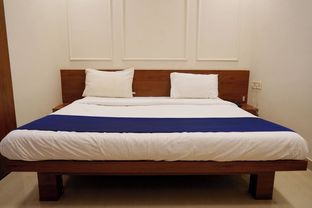 A bed with a wooden headboard, white bedding, and a blue accent.